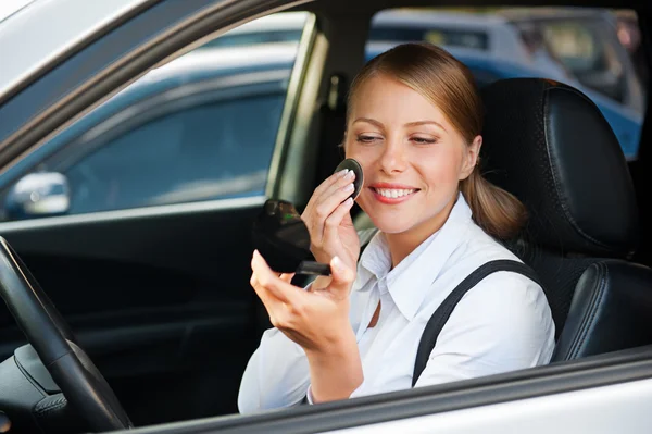 Mujer sentada en auto y aplicando maquillaje — Foto de Stock