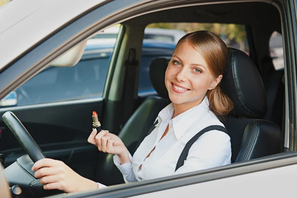 Woman sitting in the car and holding lipstick — Stock Photo, Image