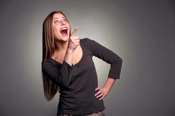 Förvånad kvinnan skrattar och pekar uppåt — Stockfoto