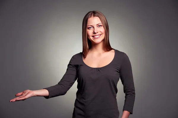 Woman holding open palm over dark background — Stock Photo, Image