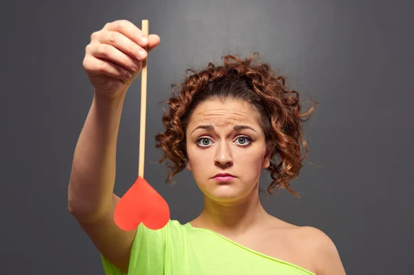 Sad young woman holding red heart — Stock Photo, Image
