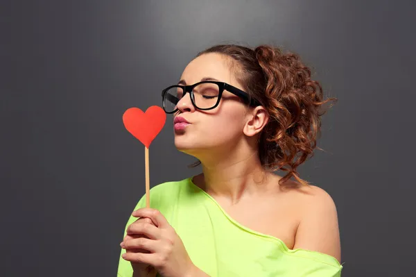 Jovem mulher em óculos beijando papel coração — Fotografia de Stock