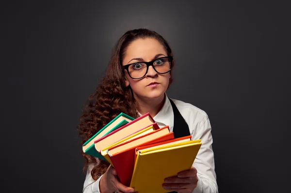 Серьезная молодая женщина в очках предлагает книги — стоковое фото