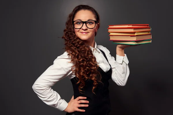 Smiley teacher holding pile of books — Stock Photo, Image