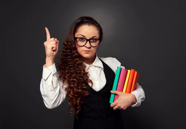 Young woman in glasses with pile of books make attention sign — Stock Photo, Image