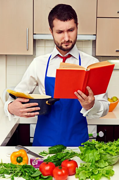 Koncentrált fiatalember olvasó cookbook — Stock Fotó