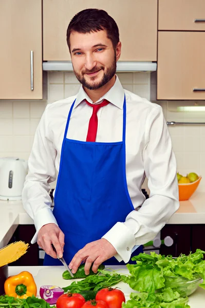 Человек в синем фартуке готовится на кухне — стоковое фото