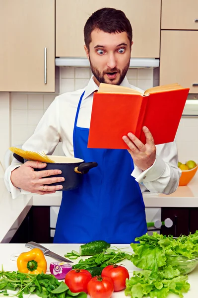 Surprised young man with cookbook — Stock Photo, Image