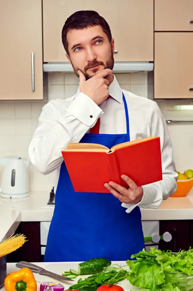 Cocinero joven con libro de cocina pensando en la receta — Foto de Stock