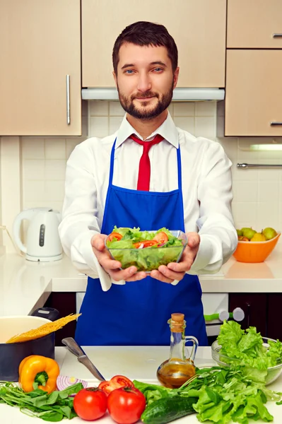 Healthy man in blue apron holding salad — Stock Photo, Image