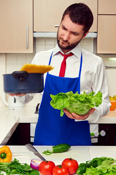Человек держит салат и сковородку со спагетти — стоковое фото