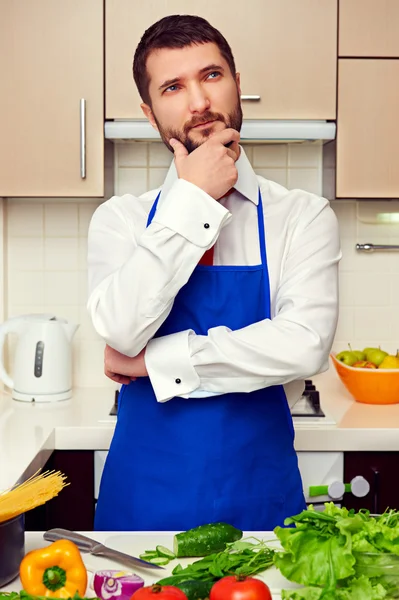 Man in blue apron thinking and looking up — Stock Photo, Image