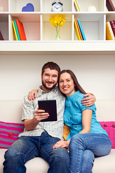 Casal sentado no sofá e segurando o tablet pc — Fotografia de Stock