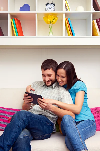 Paar sitzt auf Sofa und schaut auf den Tablet-PC — Stockfoto