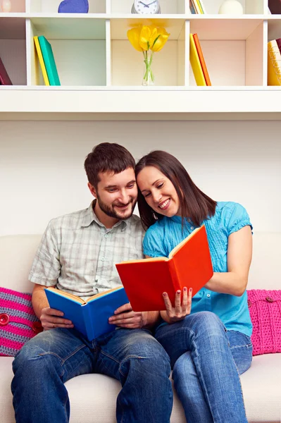 Casal sentado no sofá e lendo o livro — Fotografia de Stock