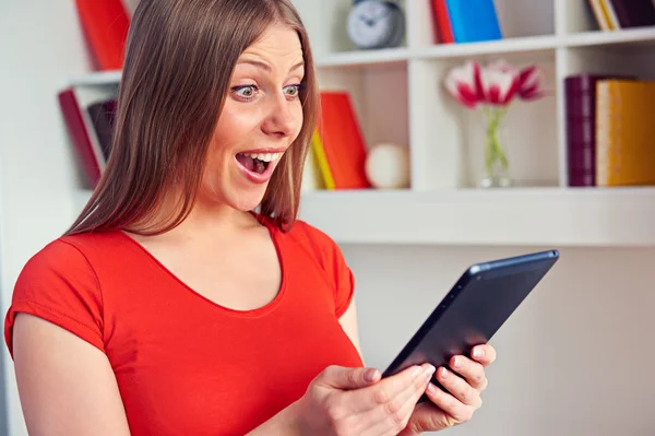Überraschte Frau blickt auf den Tablet-PC — Stockfoto