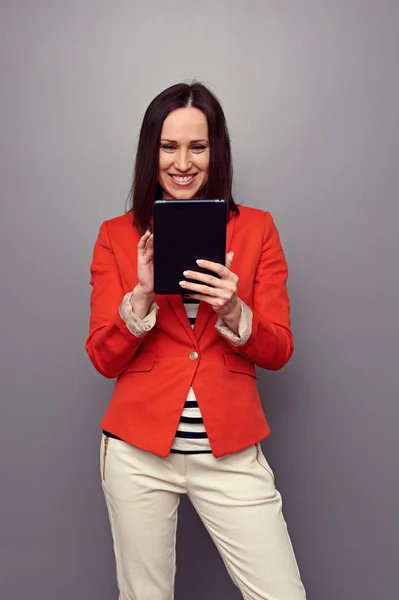 Vrouw in rode jas met behulp van tablet pc — Stockfoto