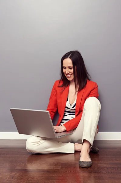 Žena sedí na podlaze a pomocí přenosného počítače — Stock fotografie
