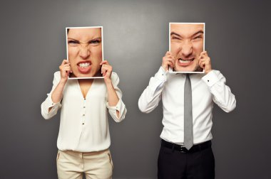 man and woman holding images with mad faces clipart