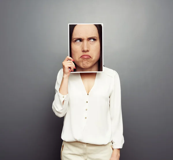 Woman covering image with big pensive face — Stock Photo, Image