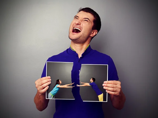 Mann hält zerrissenes Foto mit Paar in der Hand — Stockfoto