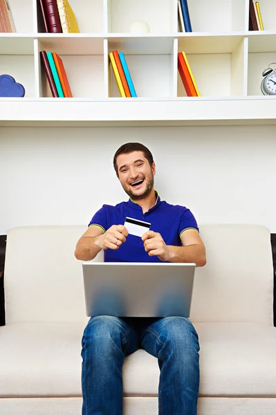 Young man showing credit card and smiling — Stock Photo, Image