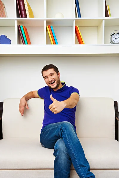 Rindo jovem sentado no sofá — Fotografia de Stock