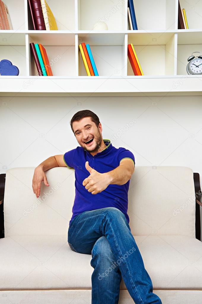 laughing young man sitting on sofa
