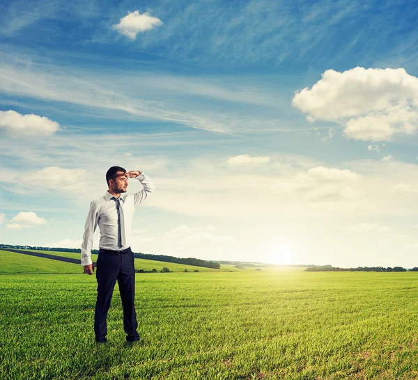 Вдумчивый человек, стоящий на зеленом поле — стоковое фото