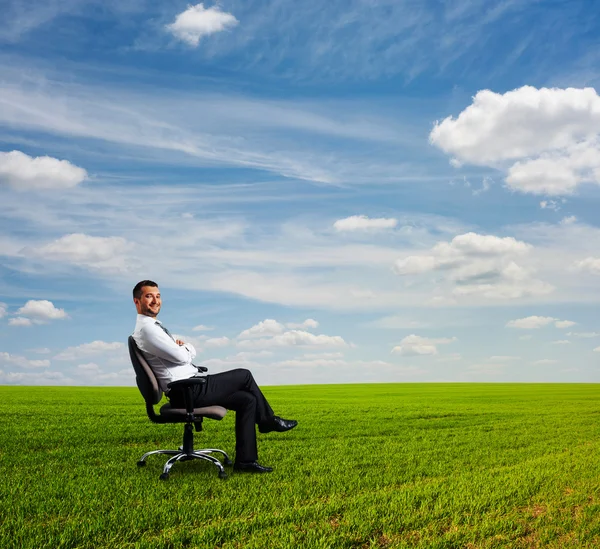 Empresário sentado no campo e descansando — Fotografia de Stock