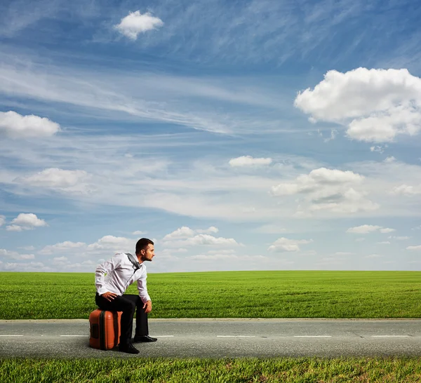 Uomo stanco seduto sulla sua borsa — Foto Stock