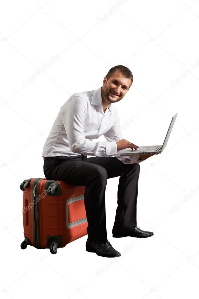 man sitting on suitcase and working