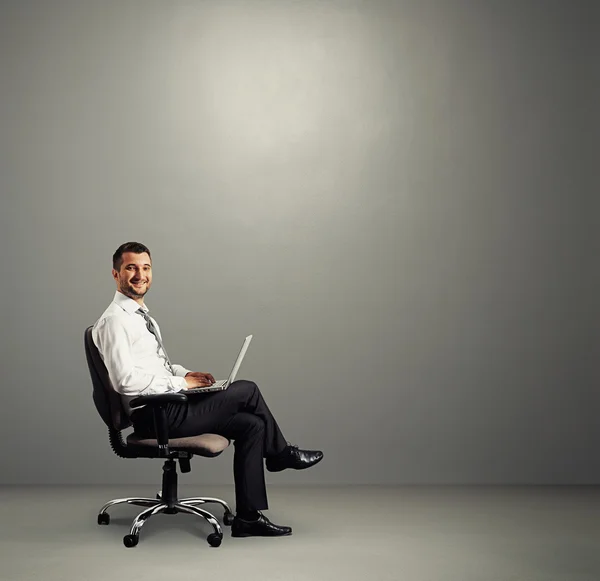 Muž s notebookem sedět v šedé místnosti — Stock fotografie