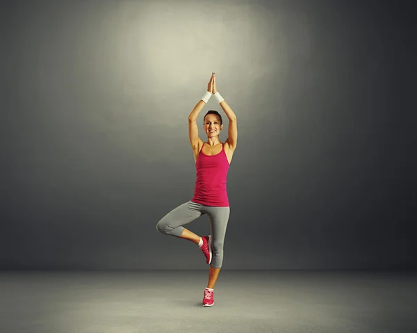 Donna che pratica yoga in studio scuro — Foto Stock