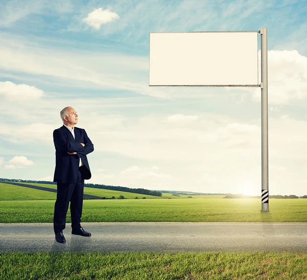 Man standing on the road against billboard — Stock Photo, Image