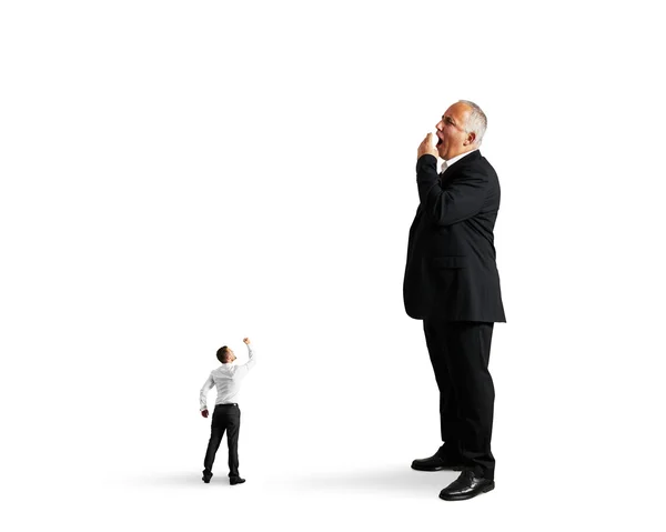 Small man showing fist to big bored businessman — Stock Photo, Image