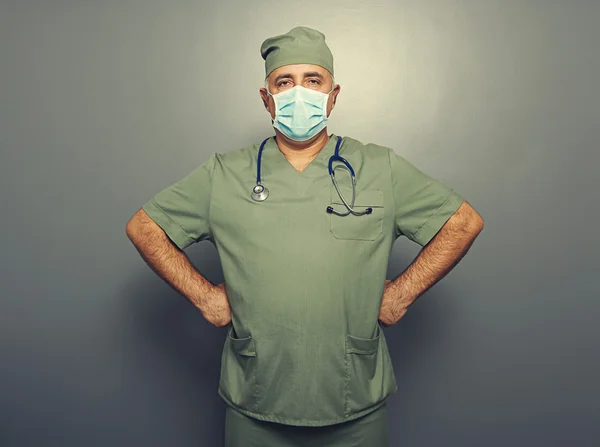 Doctor in surgeon's mask over dark — Stock Photo, Image