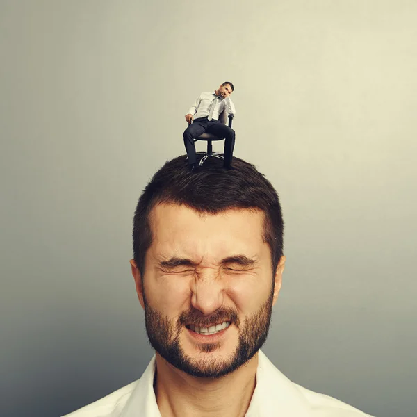 Bored small man sitting on the head — Stock Photo, Image
