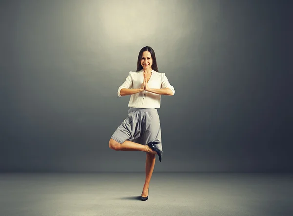 Businesswoman practicing yoga over dark — Stock Photo, Image