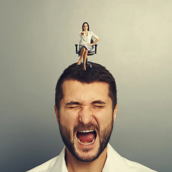 Earnest woman sitting on the screaming man — Stock Photo, Image