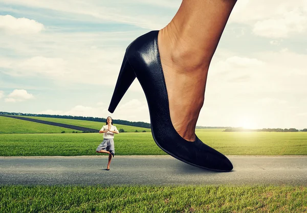 Mujer tranquila bajo el talón femenino grande —  Fotos de Stock