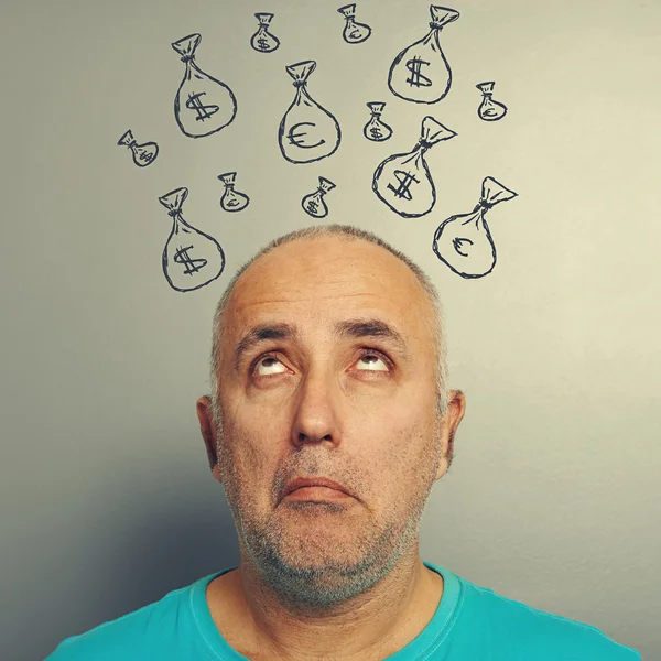 Homem sênior olhando para sacos com dinheiro — Fotografia de Stock