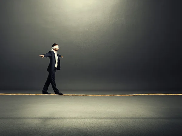 Businessman balancing on the rope over dark — Stock Photo, Image