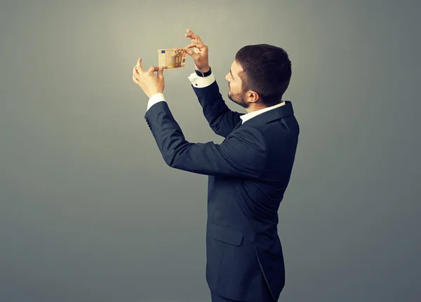 Man scrutinizing banknote over dark — Stock Photo, Image