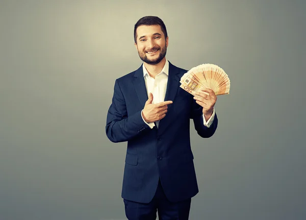 Hombre de negocios con papel moneda en la oscuridad — Foto de Stock