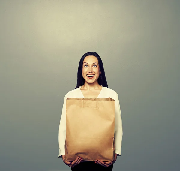 Chica feliz con bolsa de papel sobre oscuro — Foto de Stock