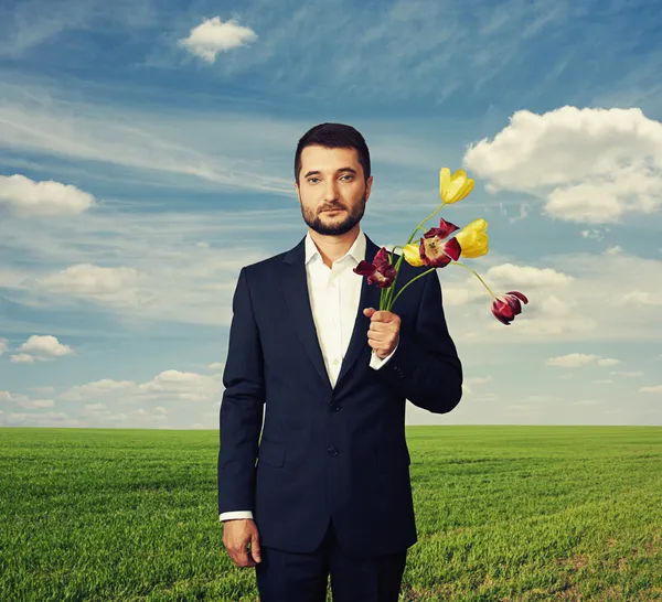 Uomo con fiori sbiaditi all'aperto — Foto Stock