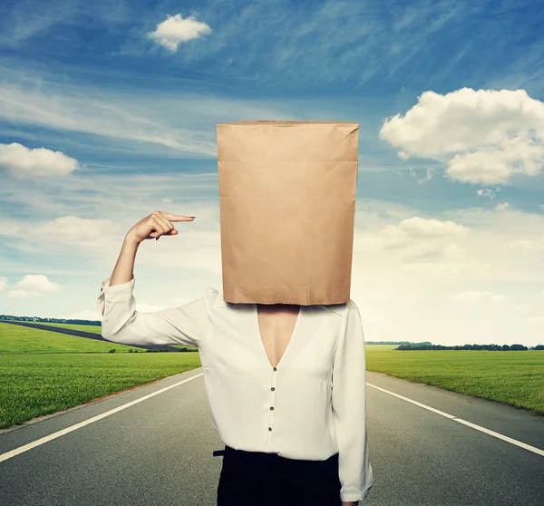 Woman pointing at paper bag on the head — Stock Photo, Image