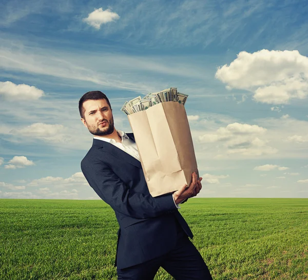 Man holding heavy bag with money — Stock Photo, Image