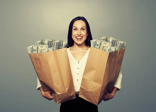 Mulher segurando dois sacos de papel com dinheiro — Fotografia de Stock